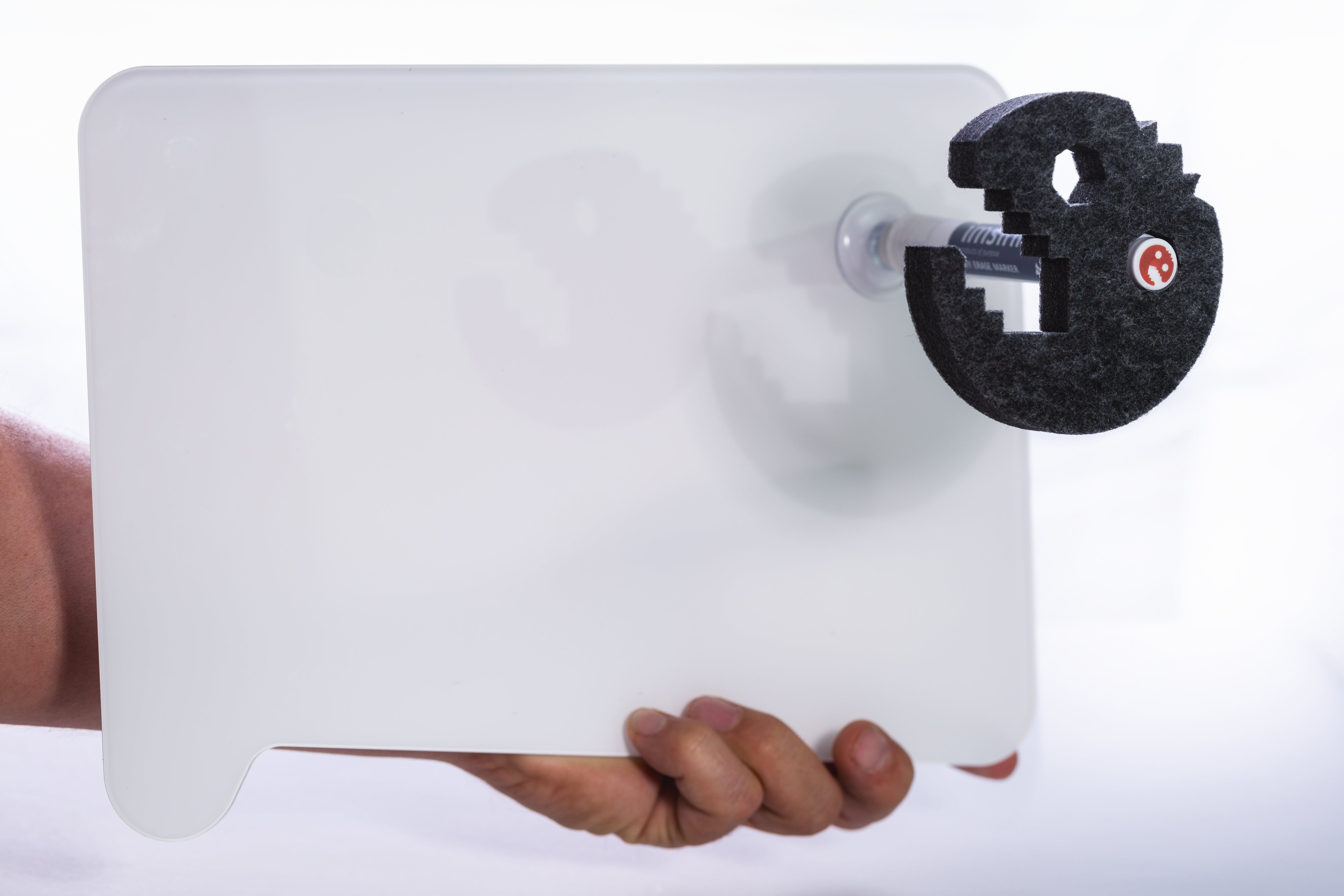 Eine Hand hält das minimalistische Whiteboard ideenbrett flat von imsinne GmbH, mit einer schwarzen Klammer in Pac-Man-Form mit kleinem roten Logo. Ideal für deine klettpunkte-Ideen vor dem schlichten, weißen Hintergrund.
